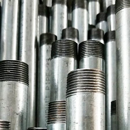 Stacked threaded metal pipes in industrial setting