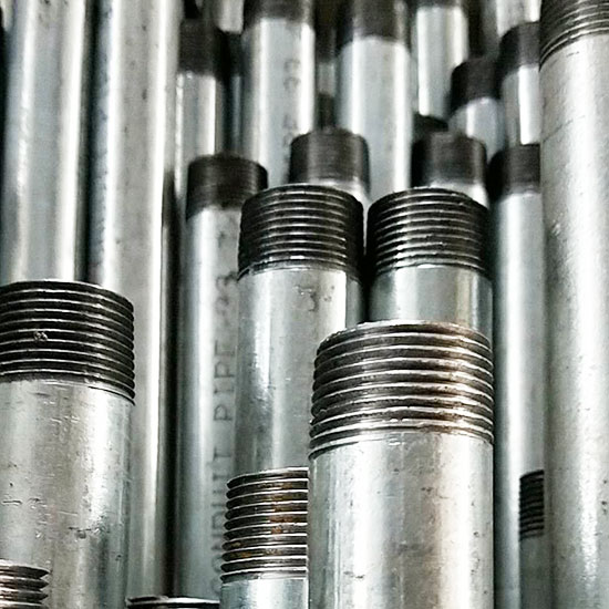 Stacked threaded metal pipes in industrial setting